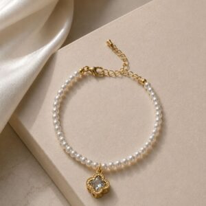 PULSERA DE SIMIL PERLAS Y ACERO DORADO CON DIJE TREBOL